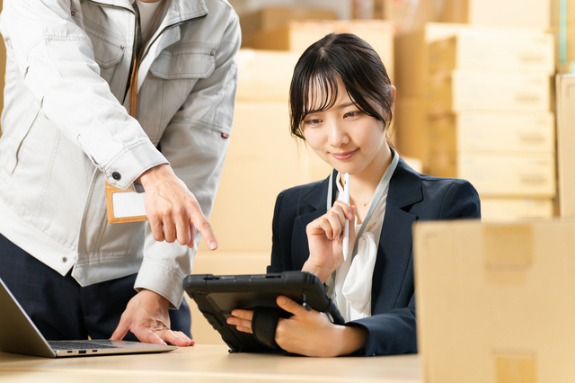 タブレットを見つめる女性と指示する作業着の